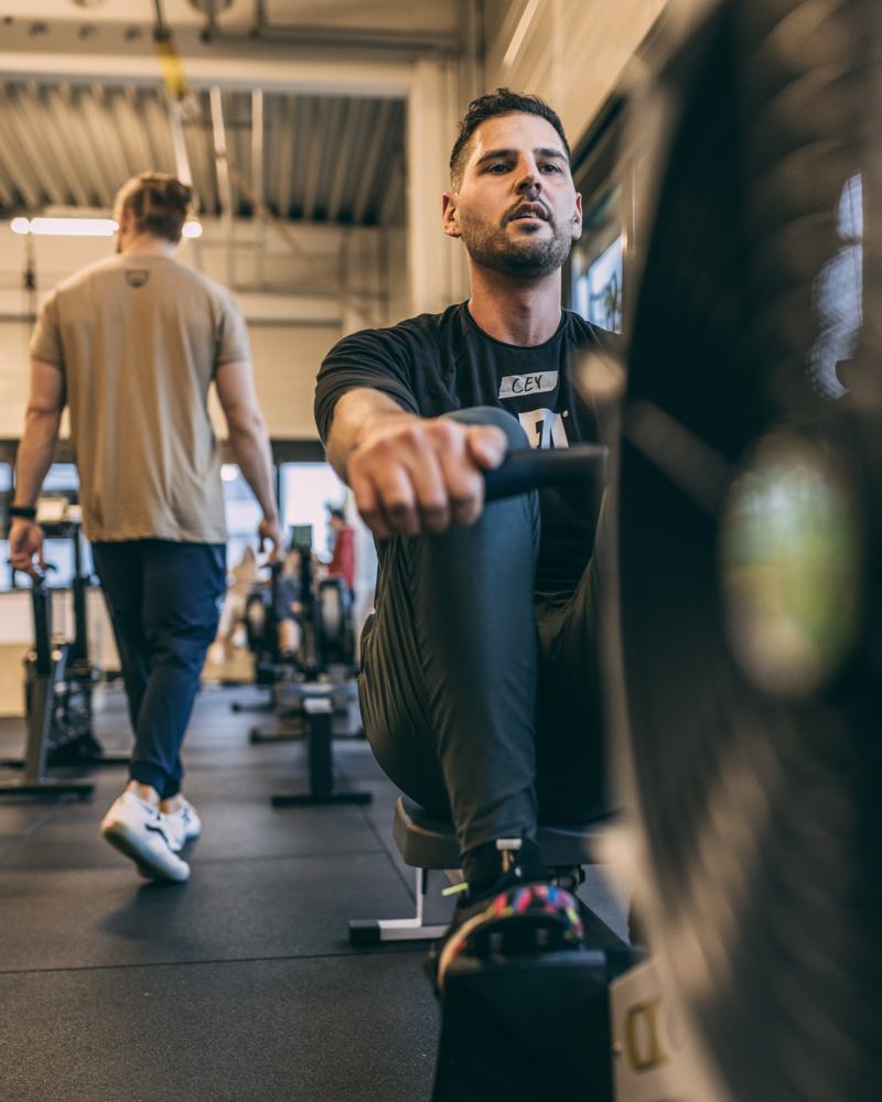 Athlet auf dem Rudergerät, im Hintergrund die Trainingsfläche der BIG BEAR Box